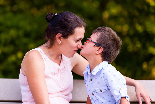 young boy with glasses kisses woman on the nose