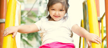 young child smiling going down a slide