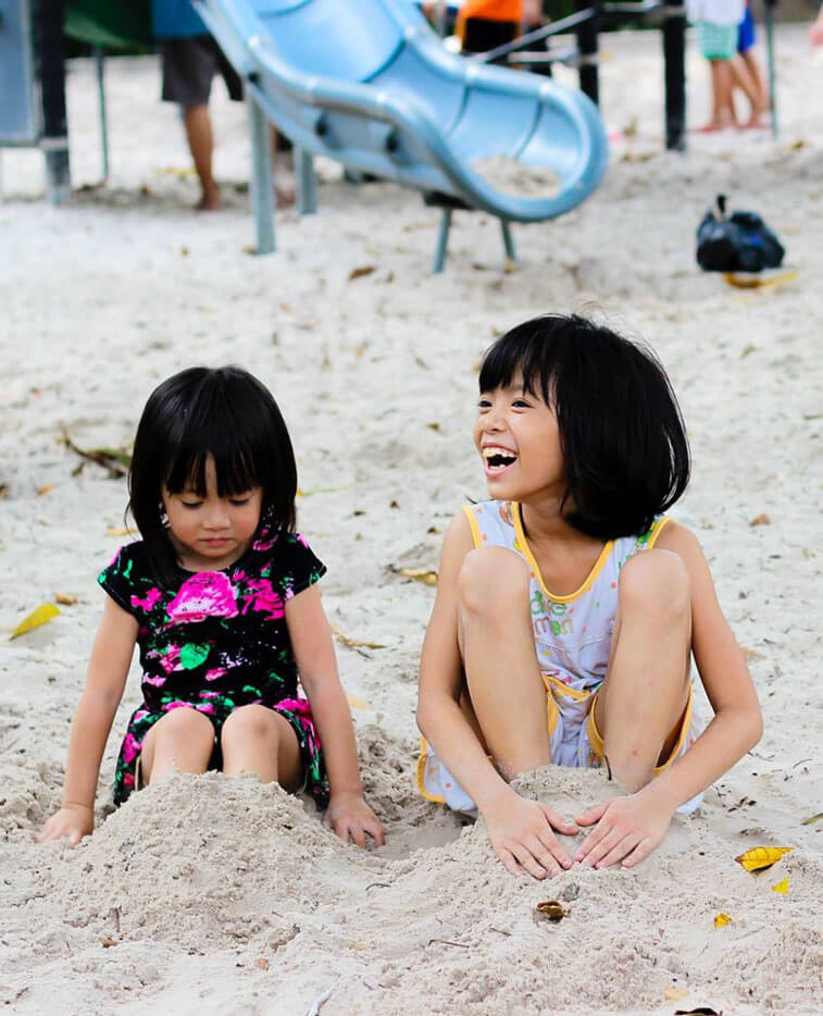 Two small children playing in the sand.